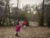 Two young black children play in their rural backyard near Memphis, Tenessee. One child wears a bright pink coat and jeans, the other a bright red vest and jeans.